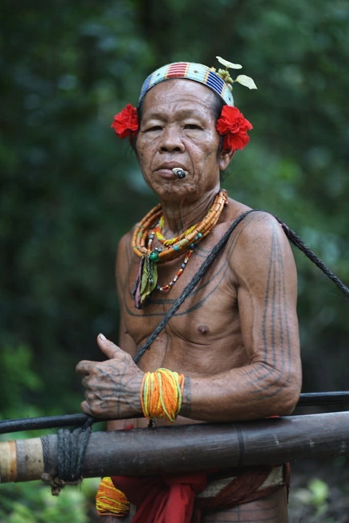 Portrait of a traditional Mentawai tribe elder wearing tribal jewelry and tattoos in West Sumatra, Indonesia.