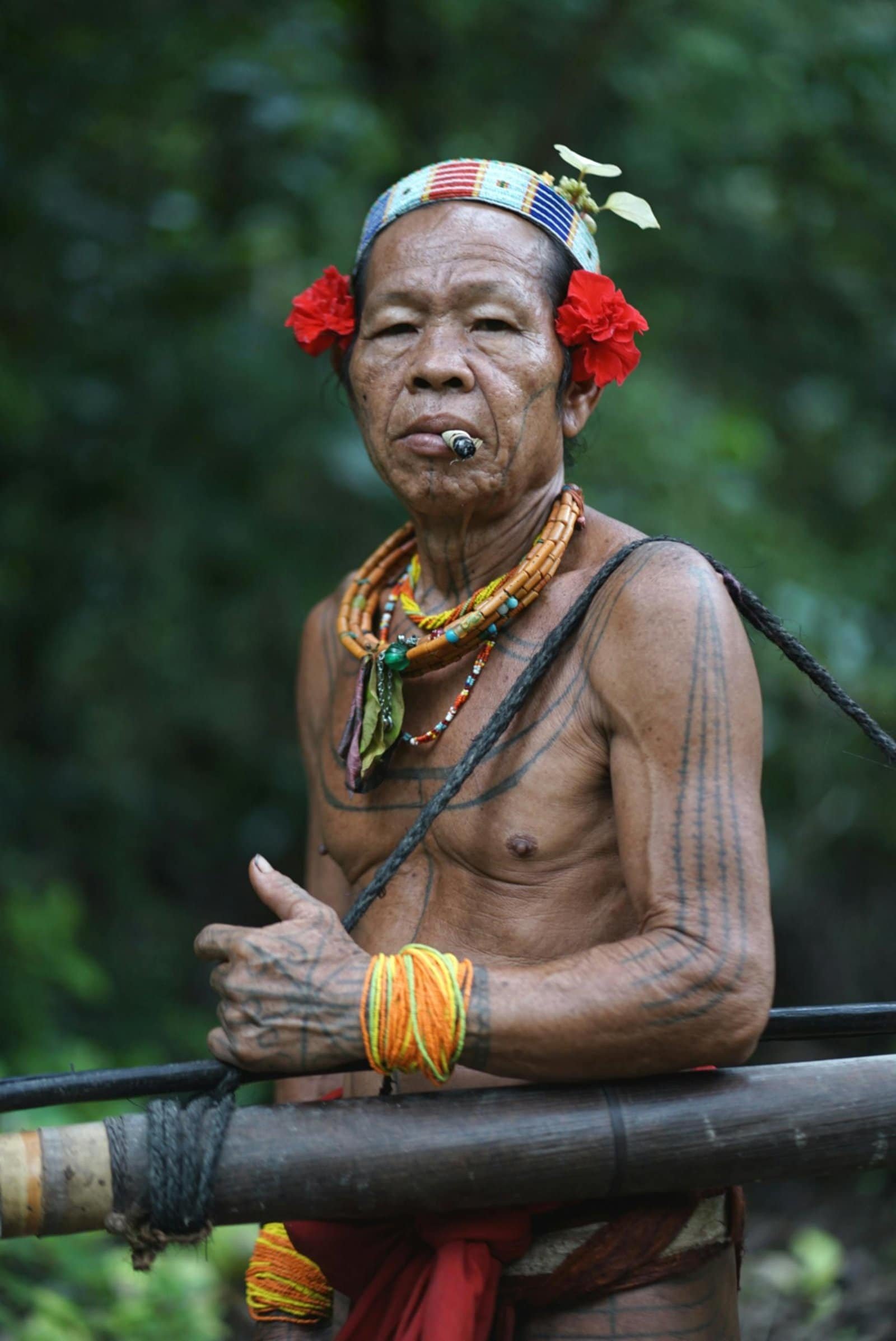 Portrait of a traditional Mentawai tribe elder wearing tribal jewelry and tattoos in West Sumatra, Indonesia.