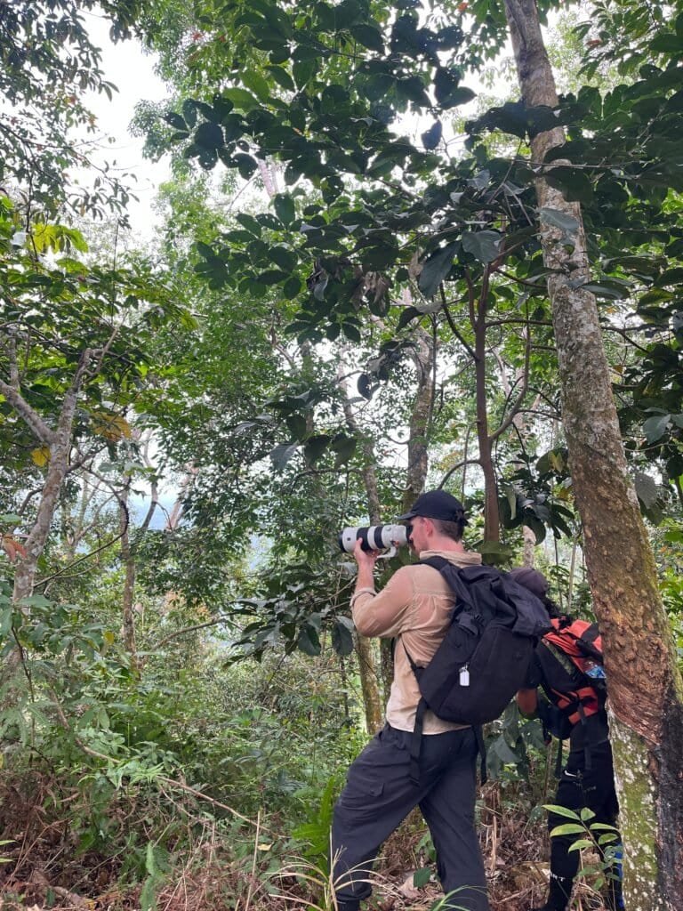 A professional wildlife photographer capturing rare species during a 5-12 Day Jungle Trekking Bukit Lawang expedition in Sumatra.